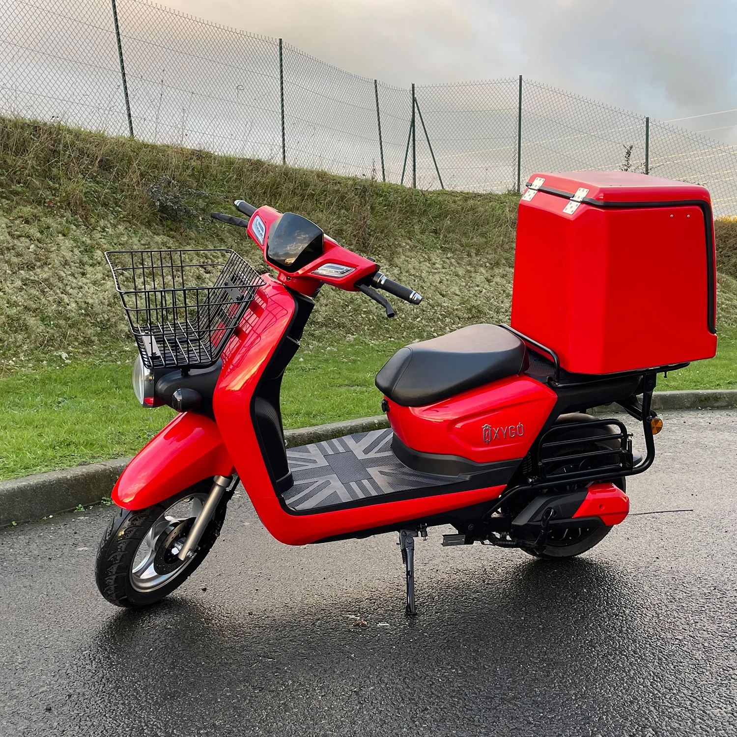Scooter électrique Cargo 50 d'Oxygo en rouge avec un top case et un panier à l'avant.